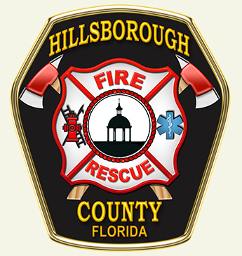A badge for Hillsborough County Fire Rescue in Florida, featuring a central image of a dome structure surrounded by various firefighter symbols including axes, a fire hydrant, and the emergency medical star of life. The words "Hillsborough County Fire Rescue Florida" are prominently displayed.