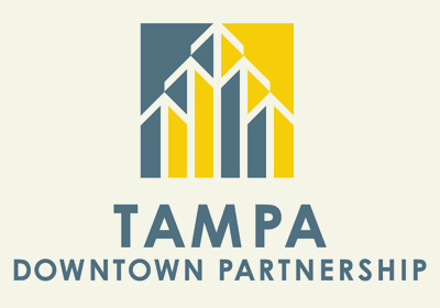 Logo for the Tampa Downtown Partnership. The design features a geometric, abstract representation of buildings in blue and yellow above the text "TAMPA" in large blue font and "DOWNTOWN PARTNERSHIP" in smaller blue font beneath.