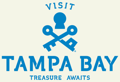 Visit Tampa Bay Logo - featuring the text "VISIT TAMPA BAY" with a keyhole symbol and crossed keys above the words. Below "TAMPA BAY," the text reads "TREASURE AWAITS." The entire design is in blue on a light background.